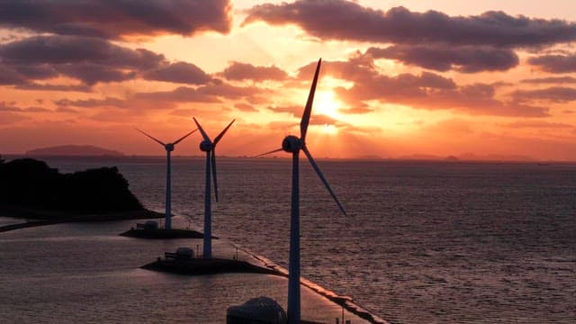 Wind turbines by the sea at sunset