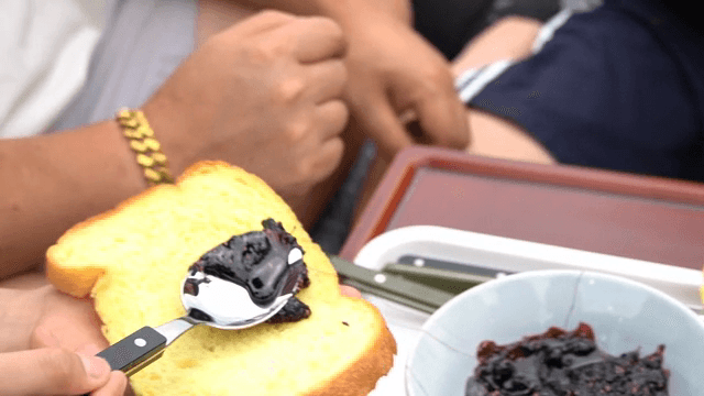 Spreading berry jam on bread slices