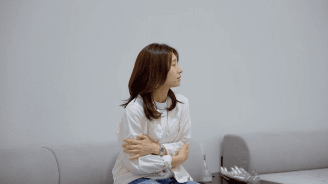 소파에 앉아 추위를 떠는 여성