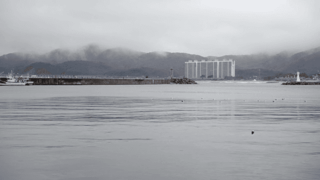멀리 등대와 건물이 보이는 잔잔한 바다