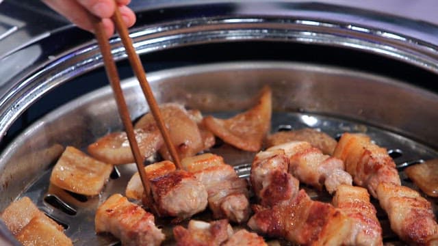 젓가락으로 집어든 지글거리는 삼겹살