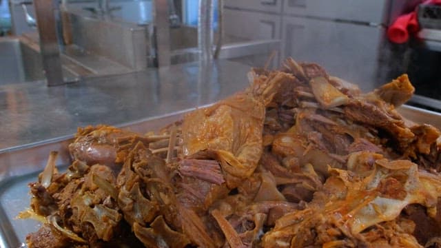 Steamed meat pieces on a metal tray in a kitchen