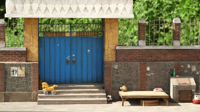 옛날 집의 파란 대문 앞에 세워진 장난감 말