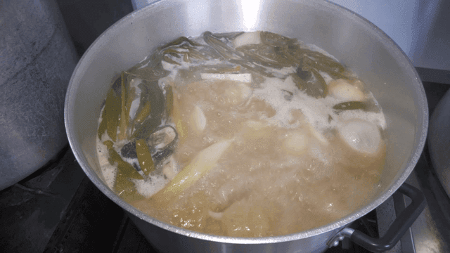Rich meat broth with vegetables boiling in a pot