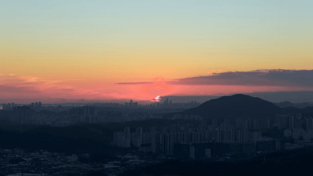 Sunset over a city skyline with mountains