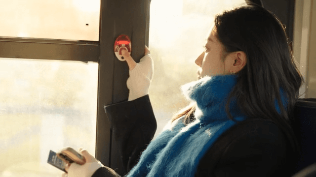 Profile of a woman pressing the stop button on a morning bus