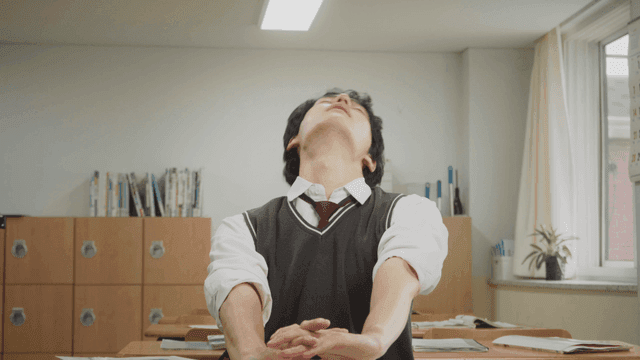 교실에서 공부하다가 기지개를 켜는 학생