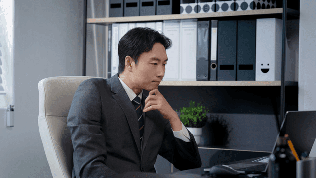 책상에서 음료를 마시며 일하는 남성