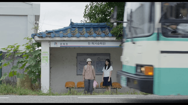 시골 버스 정류장에서 기다리는 두 여성