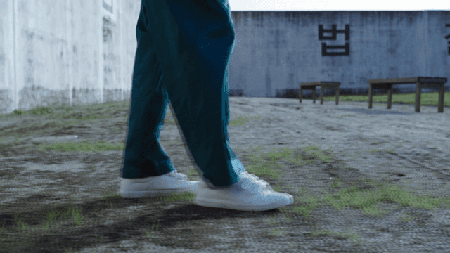 Prisoner in prison yard bouncing tennis ball