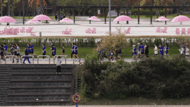 People jogging in a park with pink parasol