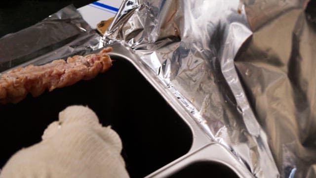 주방에서 꼬치구이에 소스를 바르는 장갑 낀 손