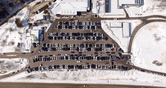 Snow-covered parking lot with many cars