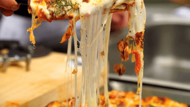 Cheesy pizza slice being lifted