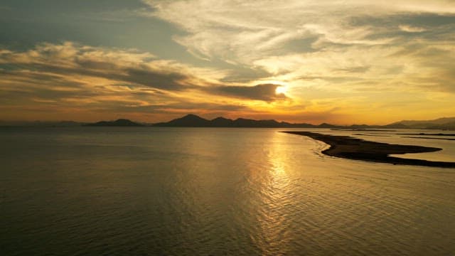 Sunset over a calm sea with distant mountains