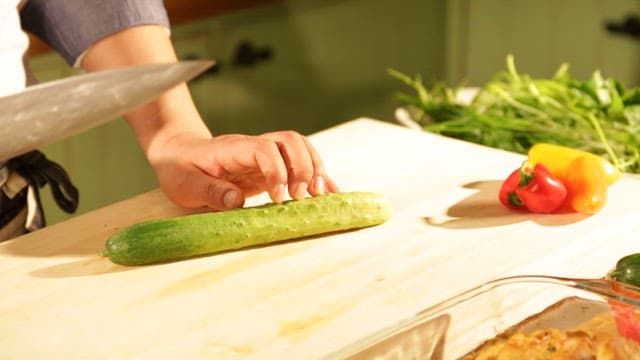 Skillfully Slicing a Cucumber in Wooden Cutting Board