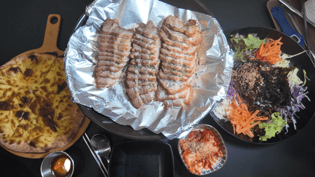 Table set with bossam, makguksu, and pizza