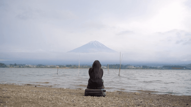 후지산이 보이는 호숫가에 앉아 있는 사람
