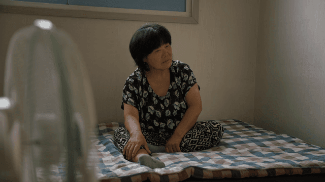 실내에서 매트에 앉아 있는 노인 여성