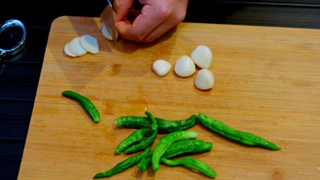 Person chopping garlic and pepper on a cutting board