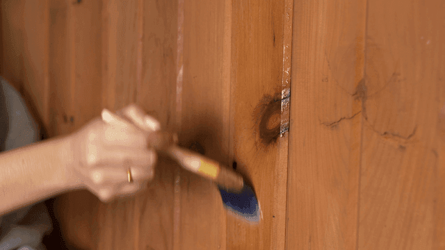 Applying varnish to a wooden wall