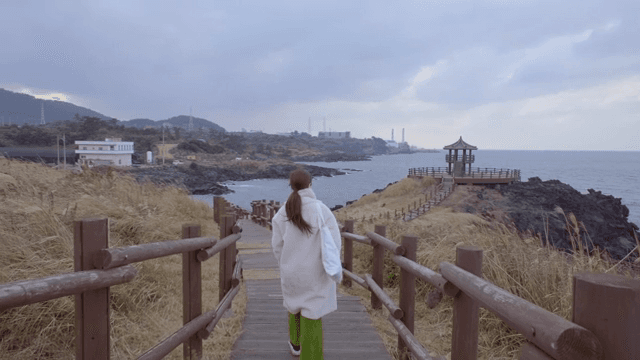 해안 길을 걷는 여성의 뒷모습