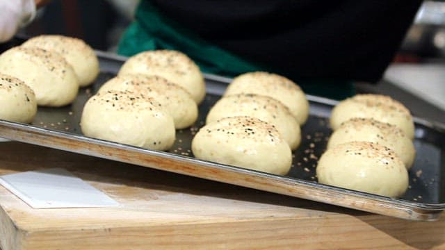 Burger bun dough sprinkled with sesame seeds