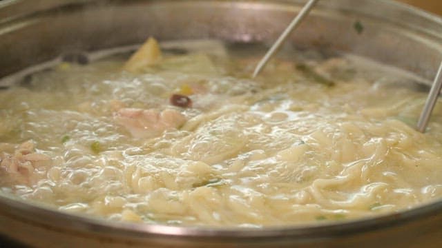 Noodles and dumplings in boiling chicken soup