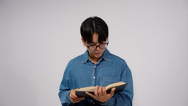 Man wearing glasses reading a book in a quiet room