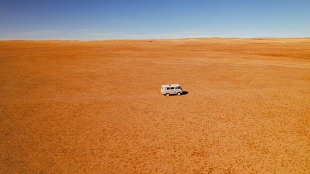 Van Traveling Across Expansive Desert Landscape