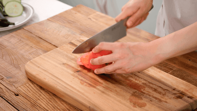 Cutting fresh tomatoes on wooden cutting board