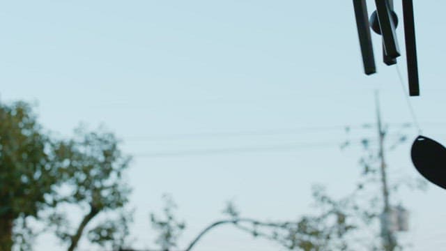 Outdoor wind chimes swinging gracefully under a clear sky.