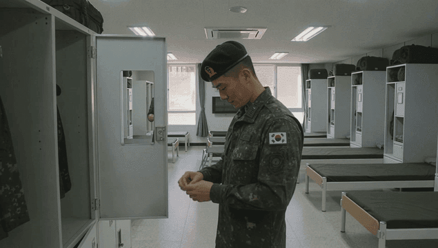 Soldier organizing his uniform while looking at cabinet in dormitory