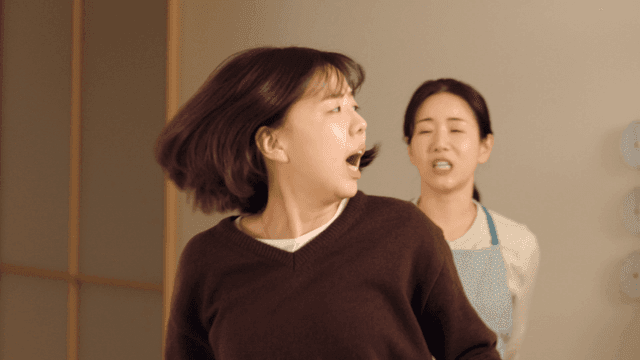 Mother slaps her daughter's back while she's looking at her phone.