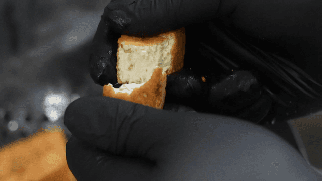 Hands breaking a piece of fried tofu