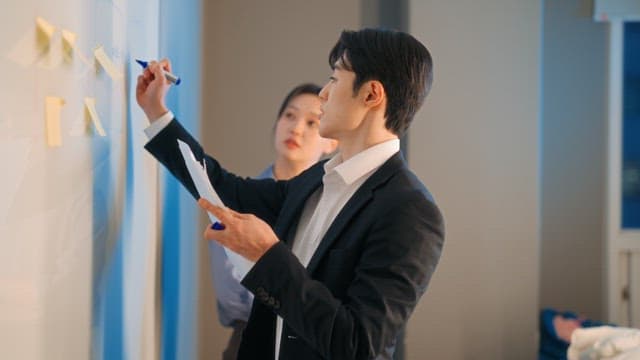 Two colleagues discussing at a whiteboard