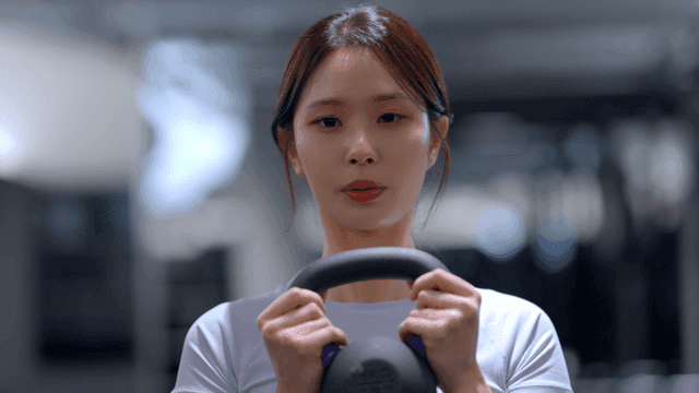Young woman doing kettlebell squat facing forward