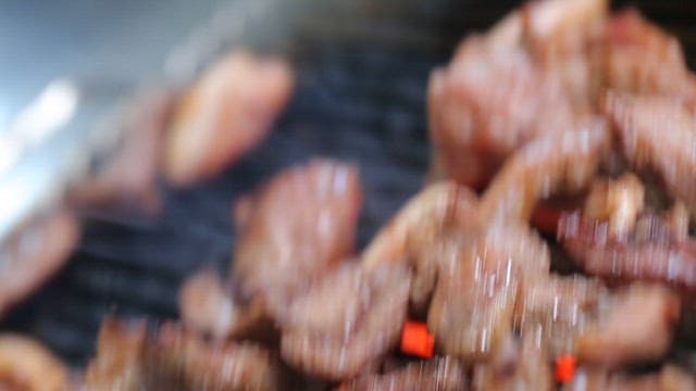 Grilled pork parts sizzling on a restaurant's barbecue grill