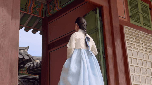 한국 전통 문으로 들어가는 한복을 입은 여성