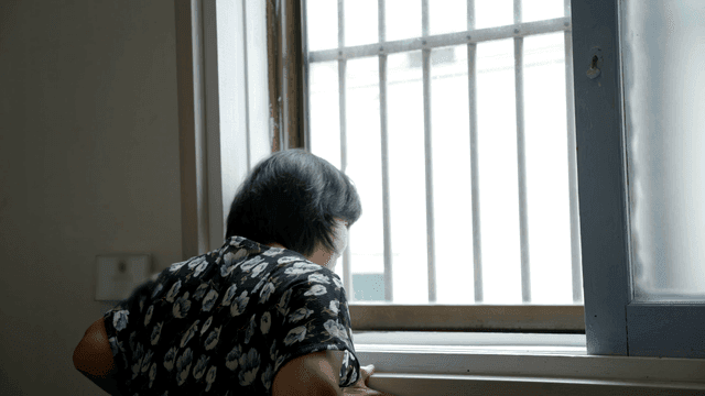 Back view of an elderly woman looking out the window