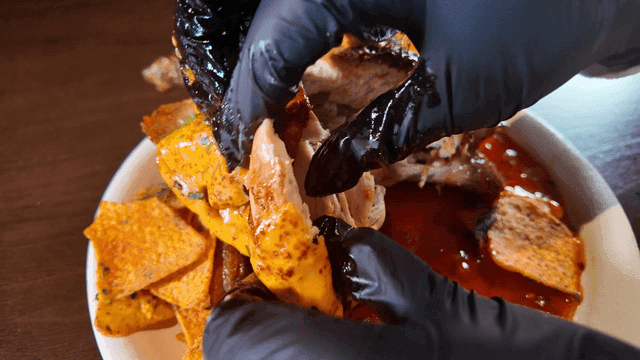 Nachos with sauce and hands tearing apart whole chicken