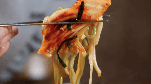 Kimchi and kalguksu noodles picked up with chopsticks