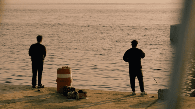 Two men fishing in evening sea
