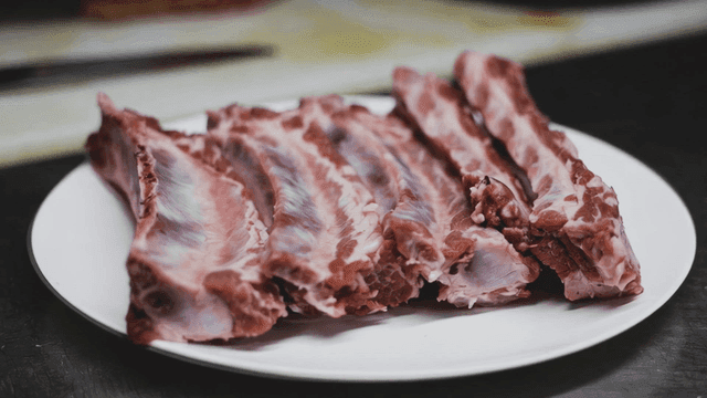 Raw ribs neatly arranged on a white plate