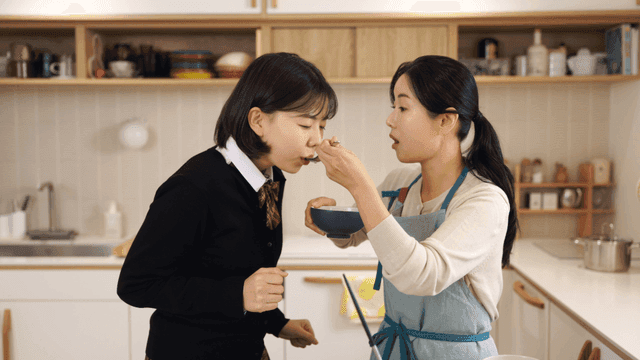 Daughter tasting food cooked by her mother in kitchen.