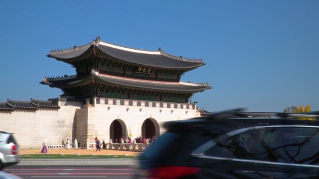 Busy street in front of Gyeongbokgung Palace, crowded with tourists under a clear blue sky