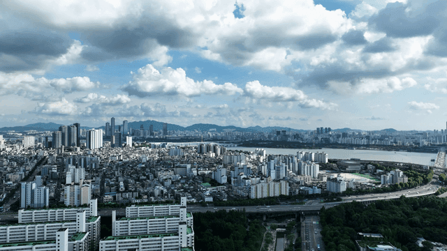 Vast city landscape beneath river and wide, cloudy sky
