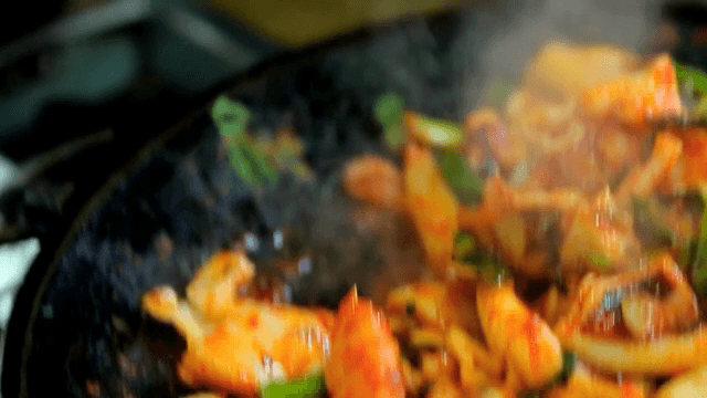 철판에서 볶아진 오징어를 젓가락으로 들어올리는 모습