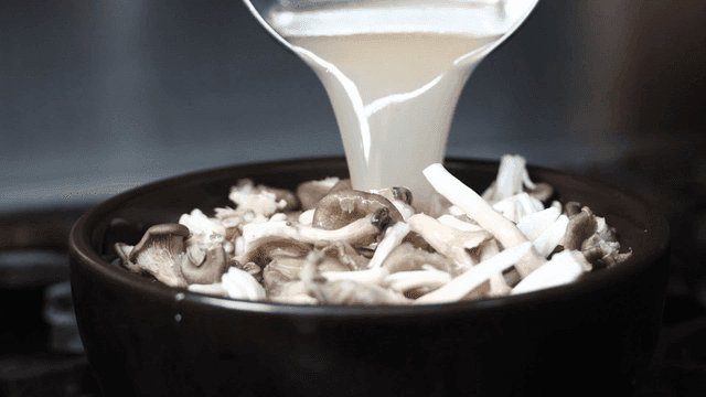 Ladle for pouring broth into bowl of mushrooms