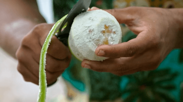 신선한 녹색 과일을 껍질 벗기는 사람